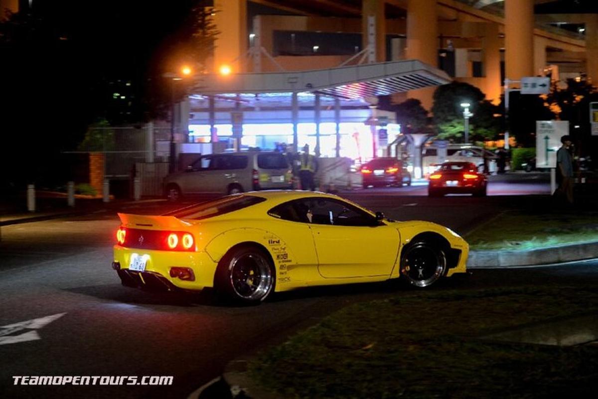 a yellow car driving down a street at night
