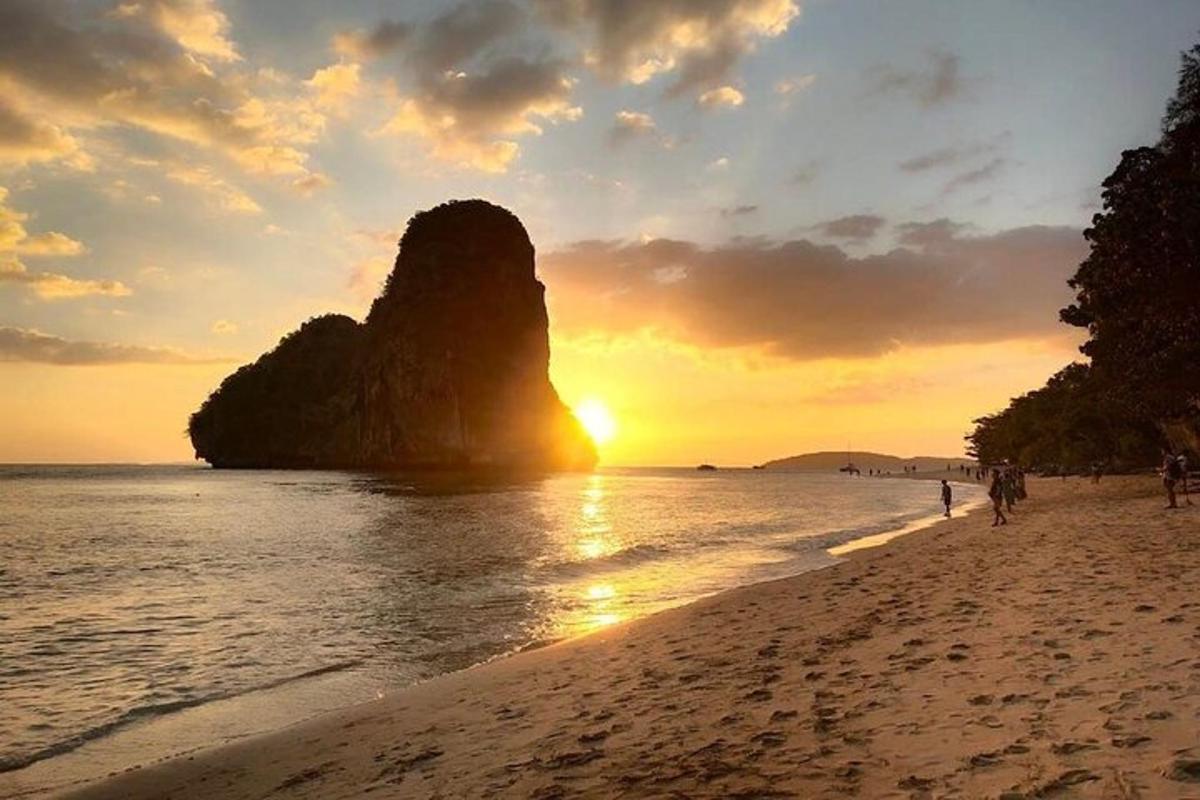 un tramonto su una spiaggia con una roccia nell'acqua