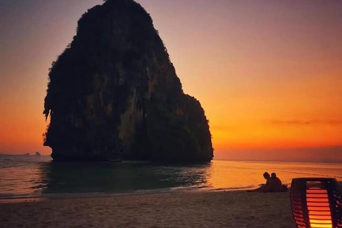 un gruppo di persone sedute su una spiaggia con una roccia