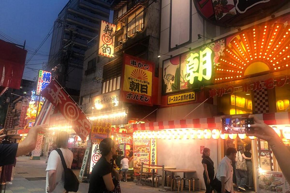 a group of people standing outside of a building with neon signs