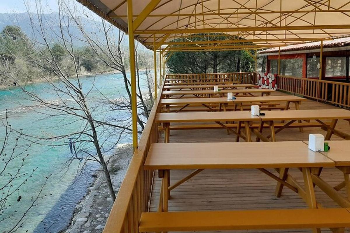 eine Reihe von Tischen auf einem Deck neben einem Fluss