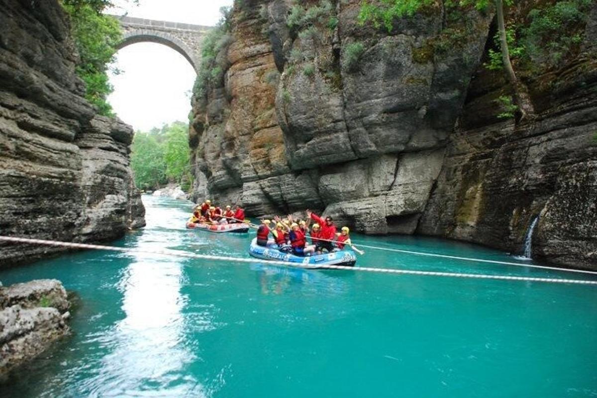Un grupo de personas en botes en un río debajo de un puente.