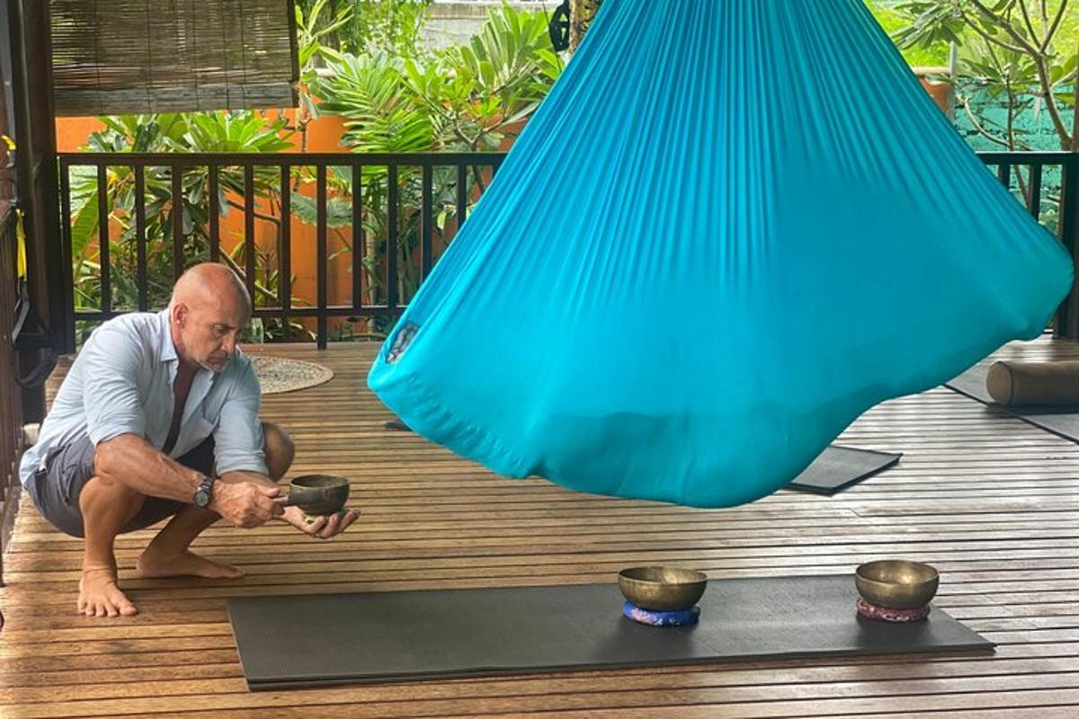 a man squatting on a wooden deck with a blue object