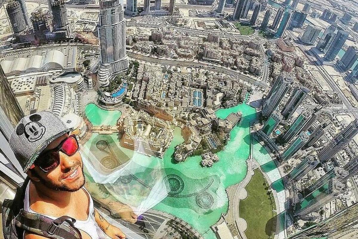 a man wearing sunglasses and a hat standing in front of a city