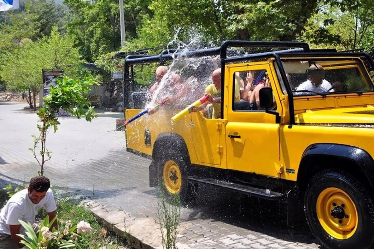 un groupe de personnes dans une jeep jaune jouant avec de l'eau