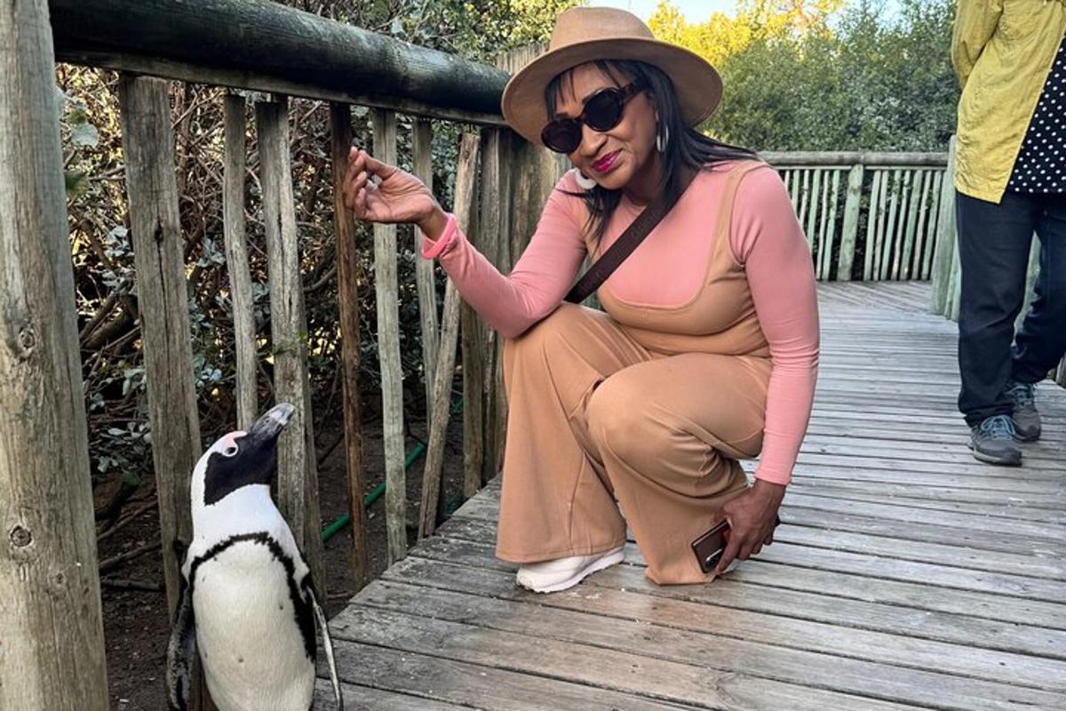 naine kükitab puusillal ja toidab pingviini