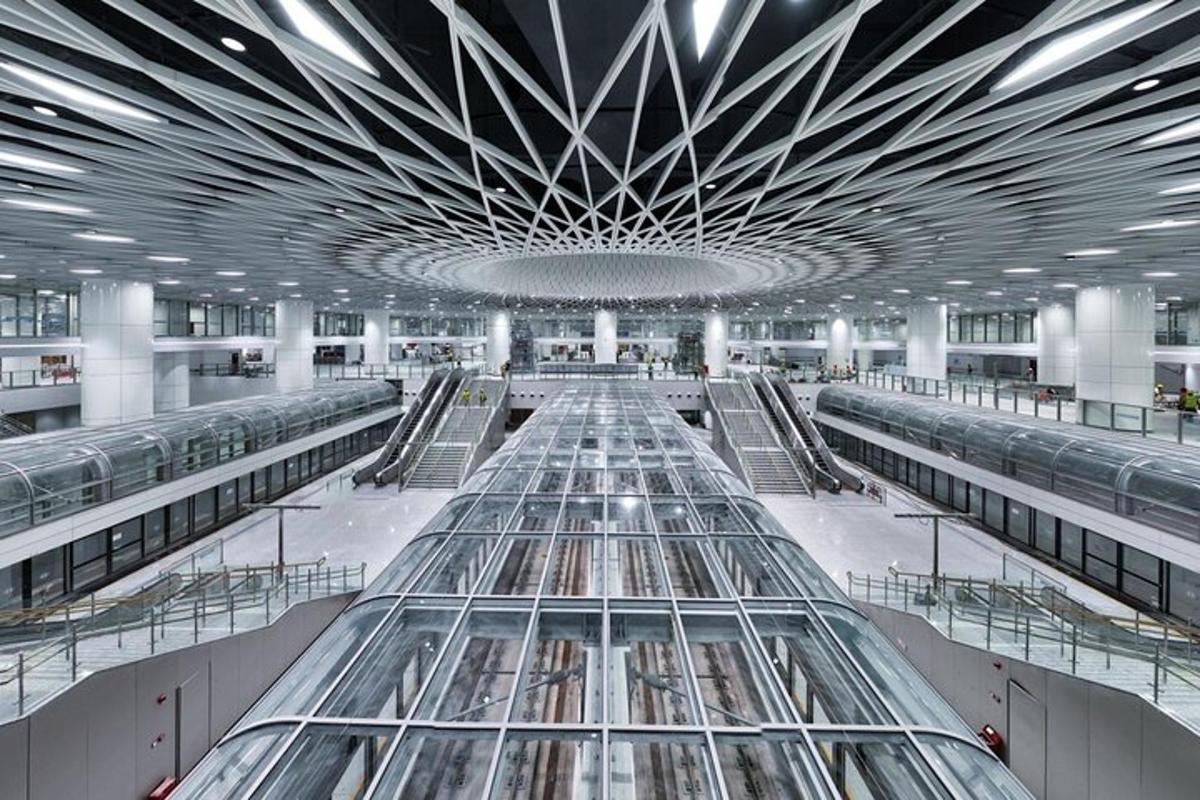 Un gran aeropuerto con techo de cristal y escaleras mecánicas.