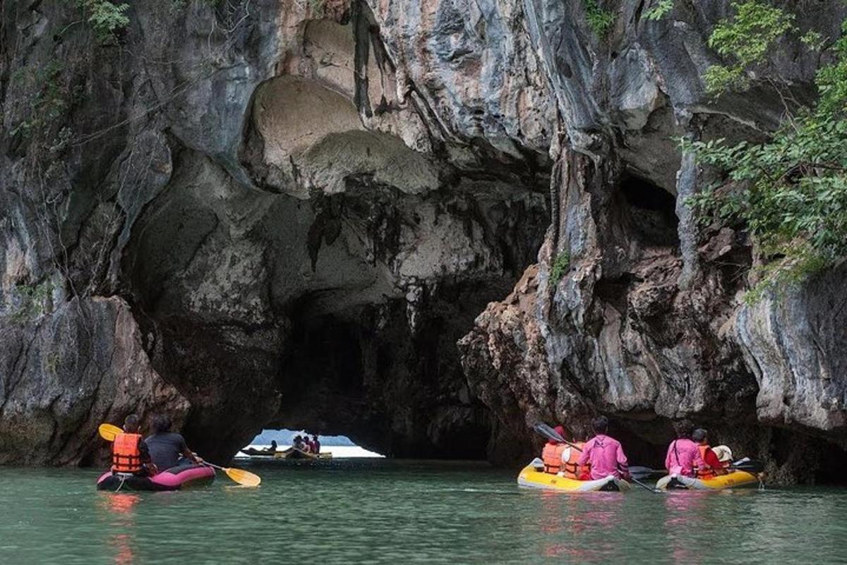 um grupo de pessoas em caiaques na água perto de uma caverna