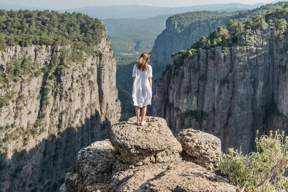 Una mujer parada sobre una roca al borde de un cañón
