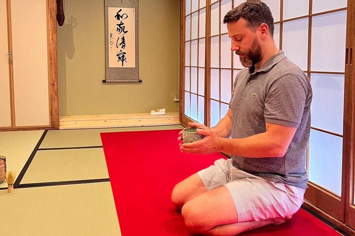 a man sitting on a red carpet holding a cup