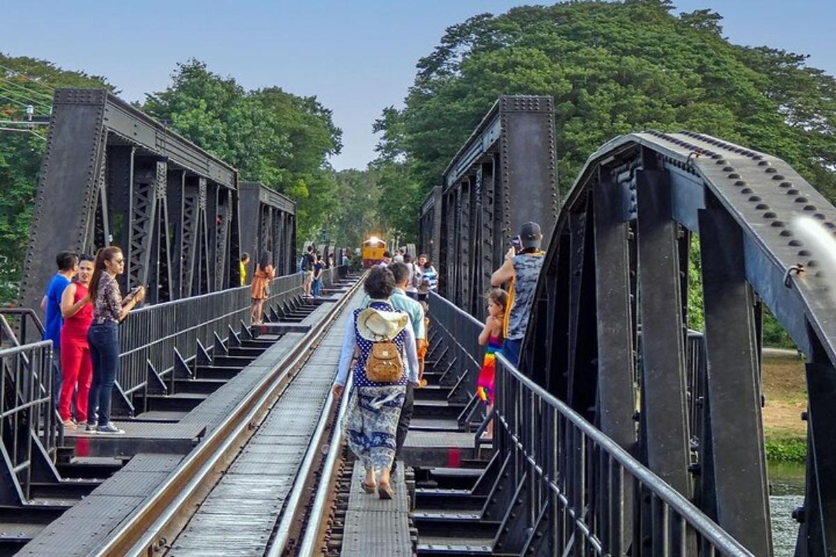un grup de oameni care așteaptă un tren pe un pod