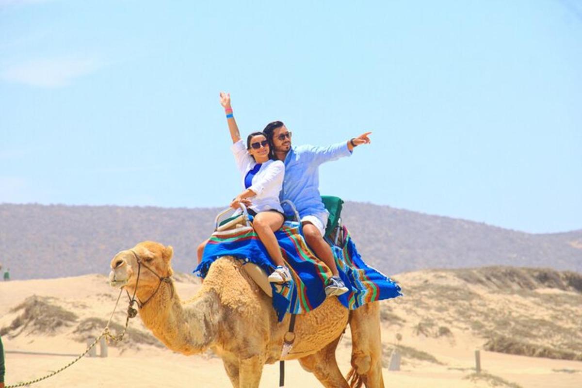a man and woman riding on a camel in the desert