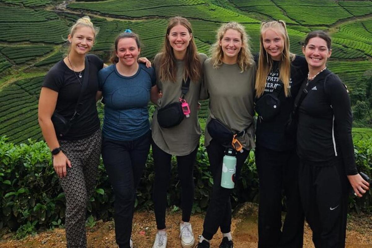 a group of women standing in front of a tea plantation