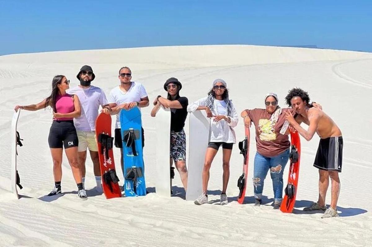 a group of people standing in the sand with snowboards