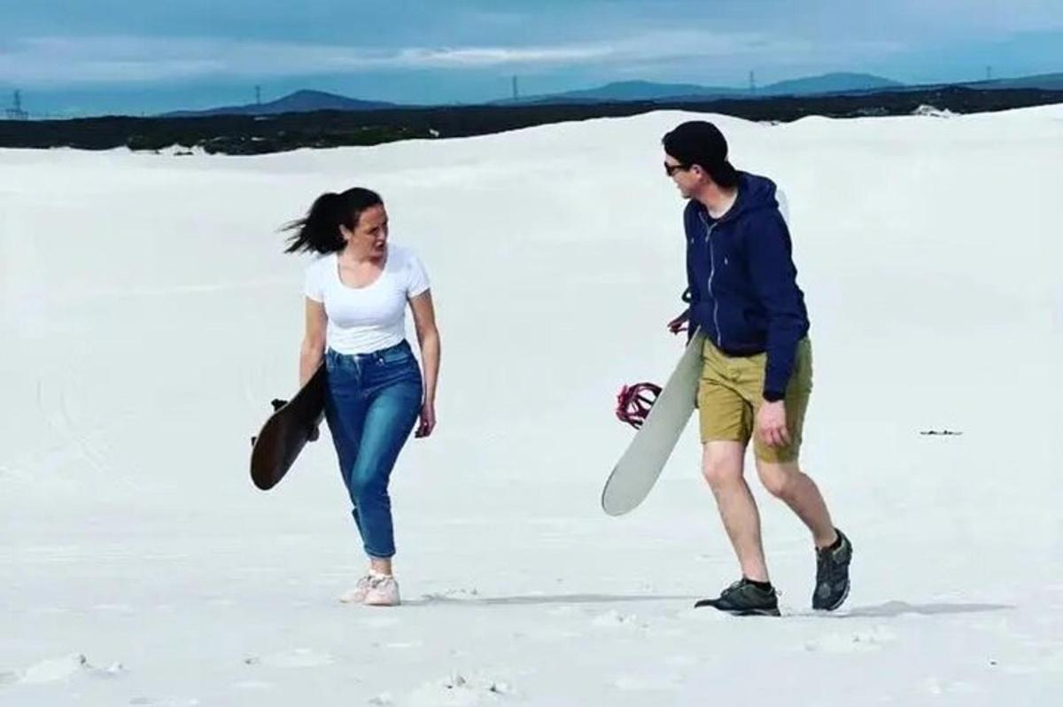 一男一女拿着冲浪板在沙滩上行走