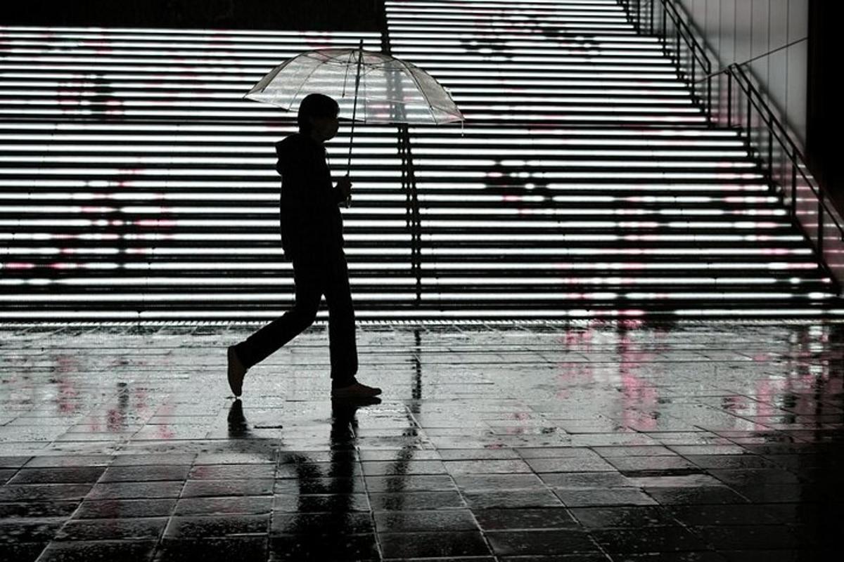 um homem caminhando na chuva com um guarda-chuva