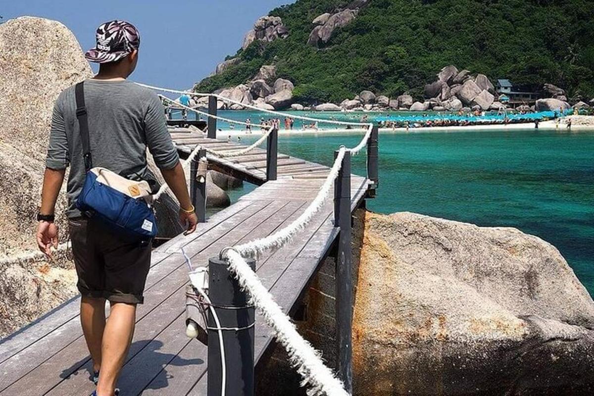 a man walking on a wooden bridge over the water
