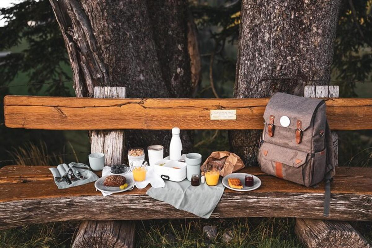 un tavolo da picnic con cibo e uno zaino su una panchina