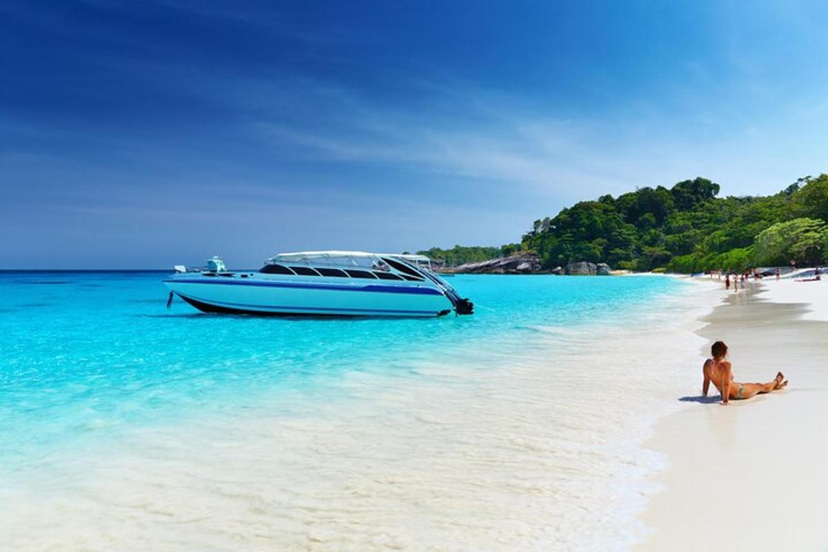 Ein Mann sitzt an einem Strand neben einem Boot