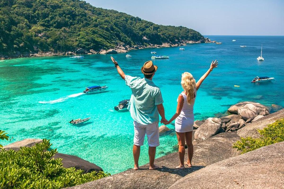 moški in ženska, ki stojita na skali s pogledom na ocean