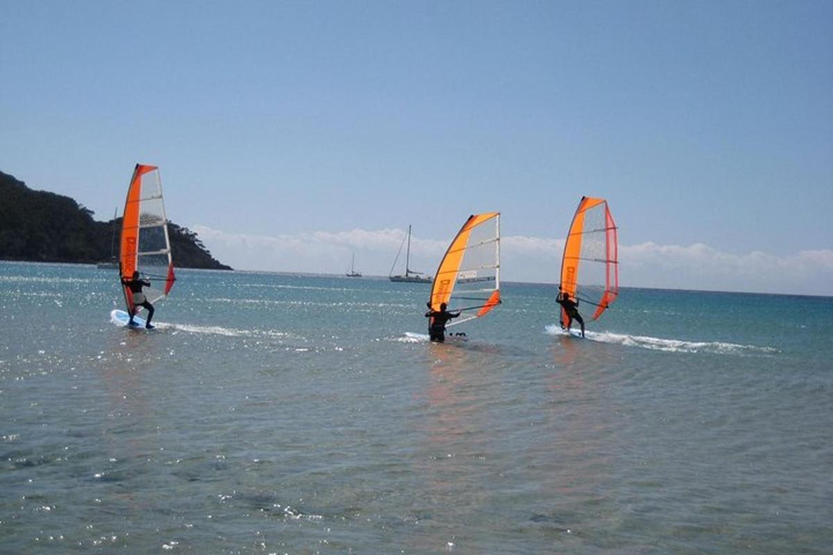 Tres personas están haciendo windsurf en el agua.