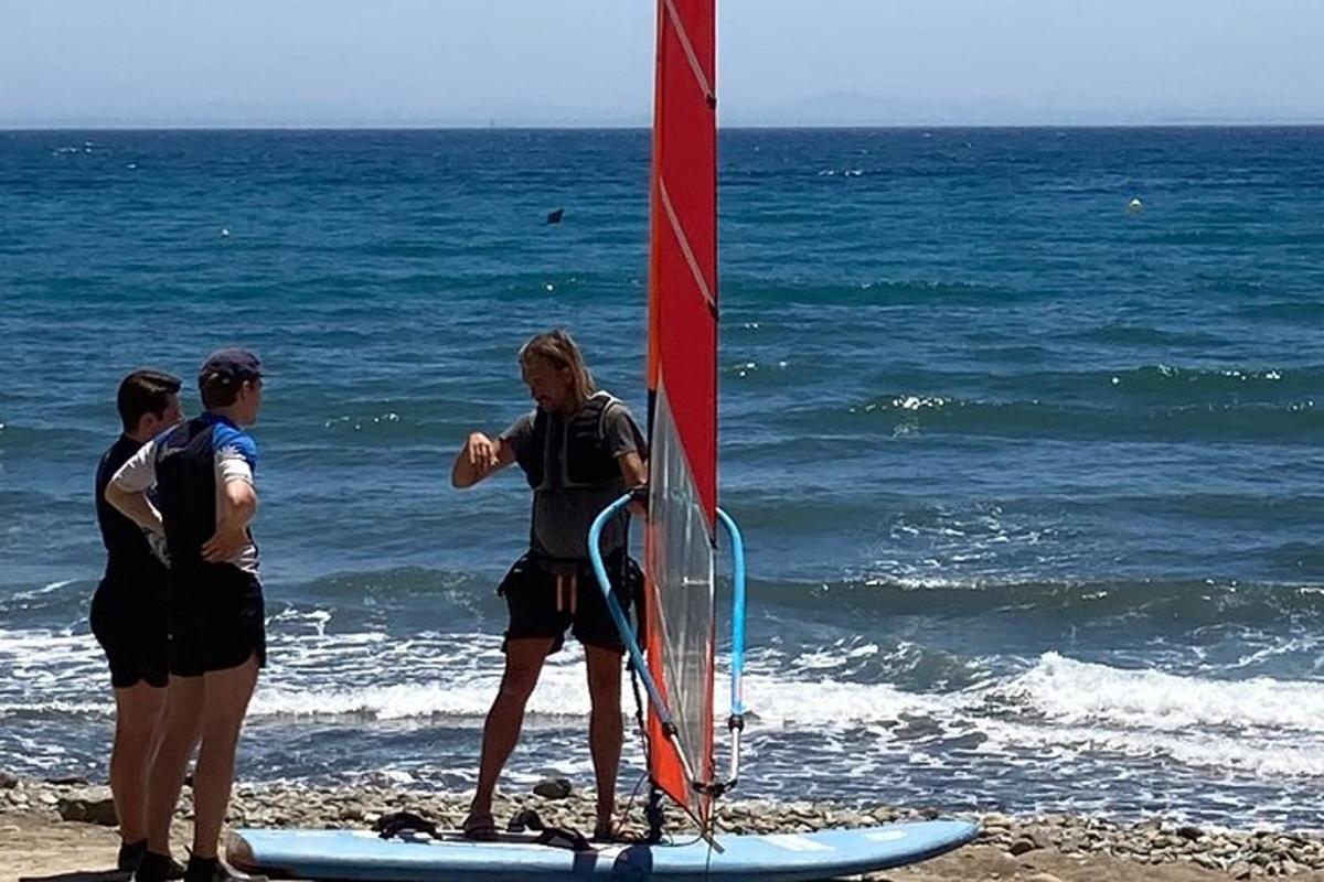 Un grupo de personas de pie en la playa con una vela.