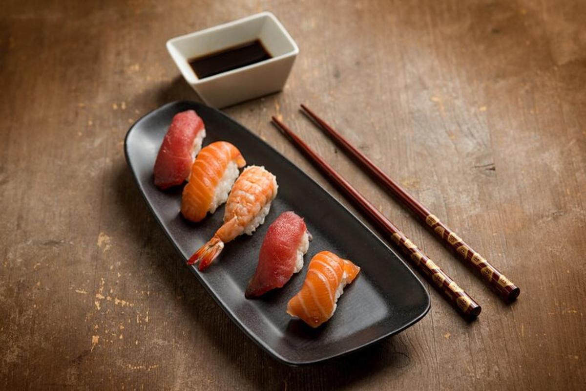 en tallrik sushi med morötter och räkor och ätpinnar