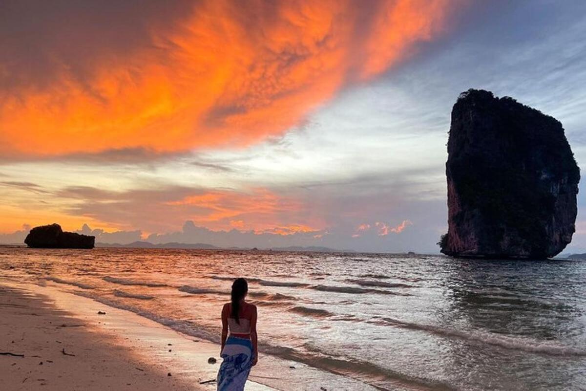 une femme marchant sur la plage avec un rocher dans l'océan