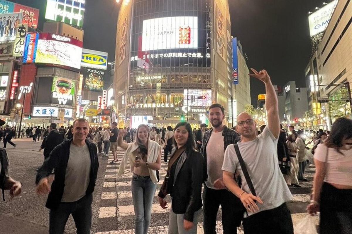 Un grupo de personas cruzando una calle concurrida de la ciudad por la noche.