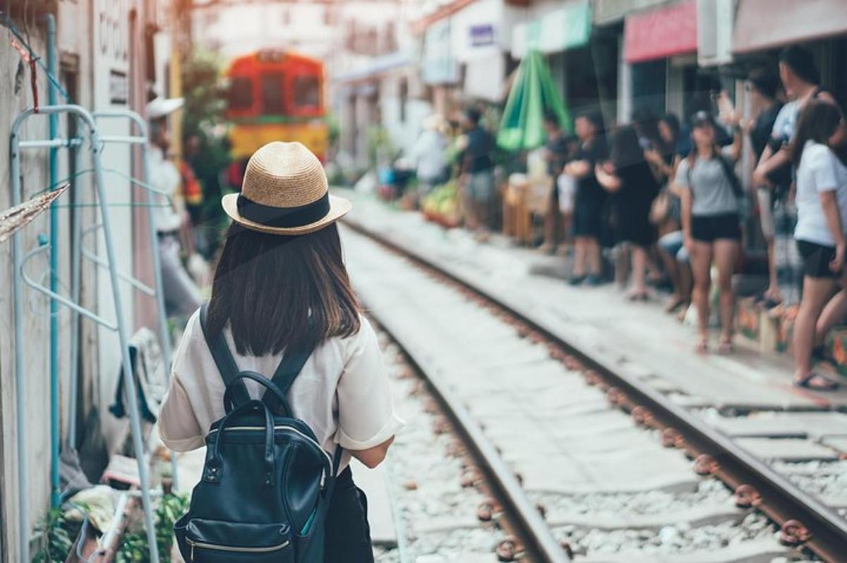 uma menina com uma mochila olhando para um trilho de trem