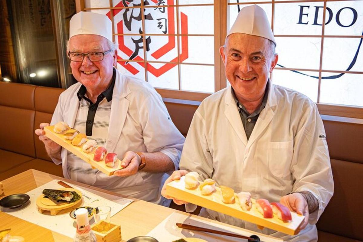 dois homens em trajes de chef segurando uma bandeja de comida