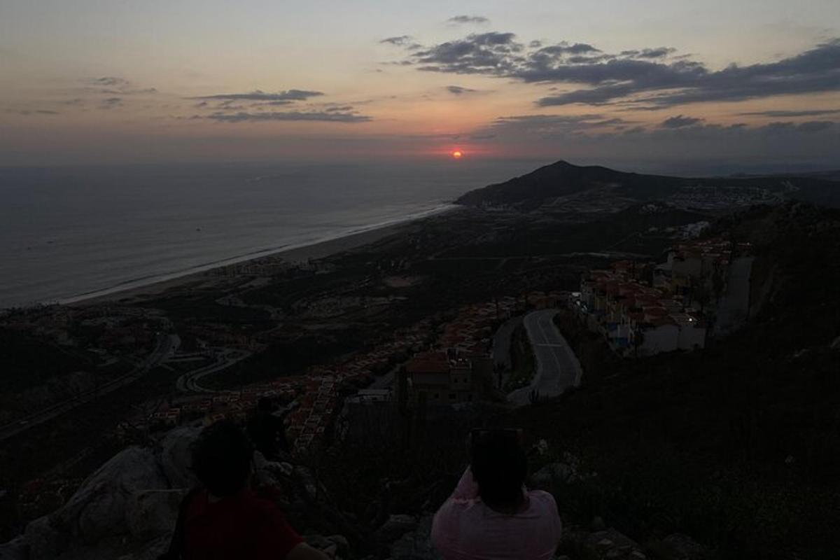 Μια ομάδα ανθρώπων που κάθονται σε ένα βουνό παρακολουθούν το ηλιοβασίλεμα