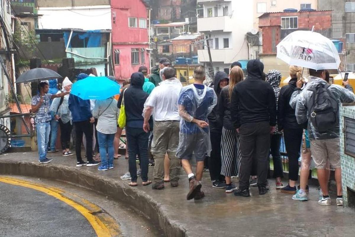 un grup de oameni care stăteau în ploaie cu umbrele