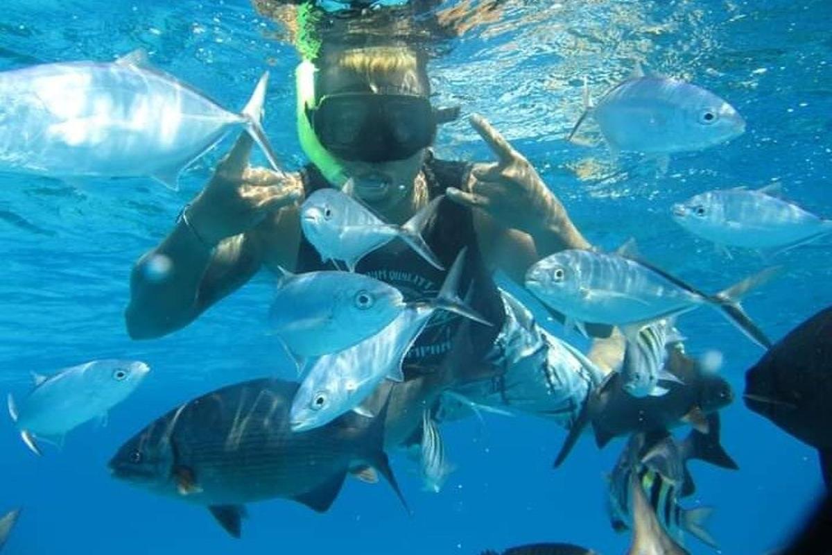 una donna in acqua con un gruppo di pesci