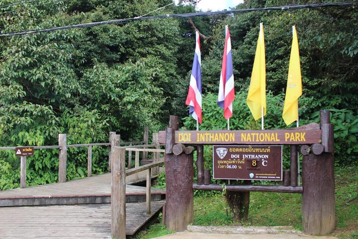 un rètol de parc amb banderes en un pont de fusta