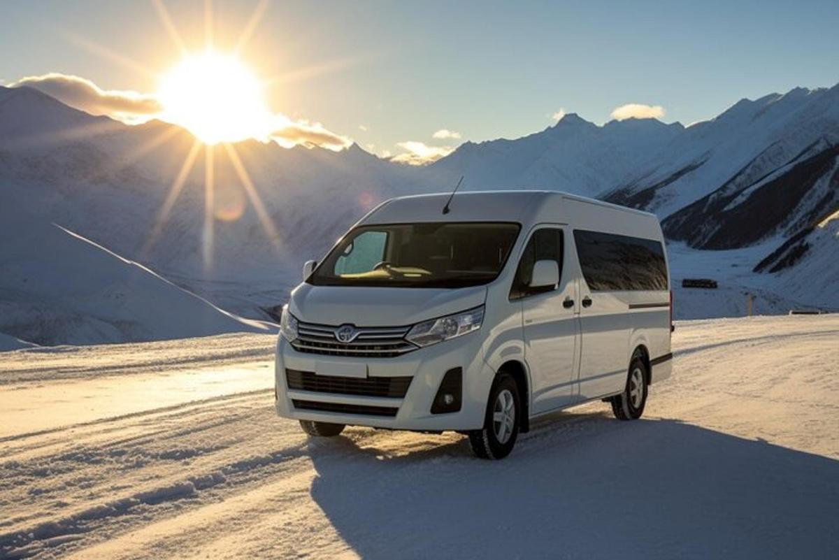 uma van branca estacionada na neve com o sol ao fundo