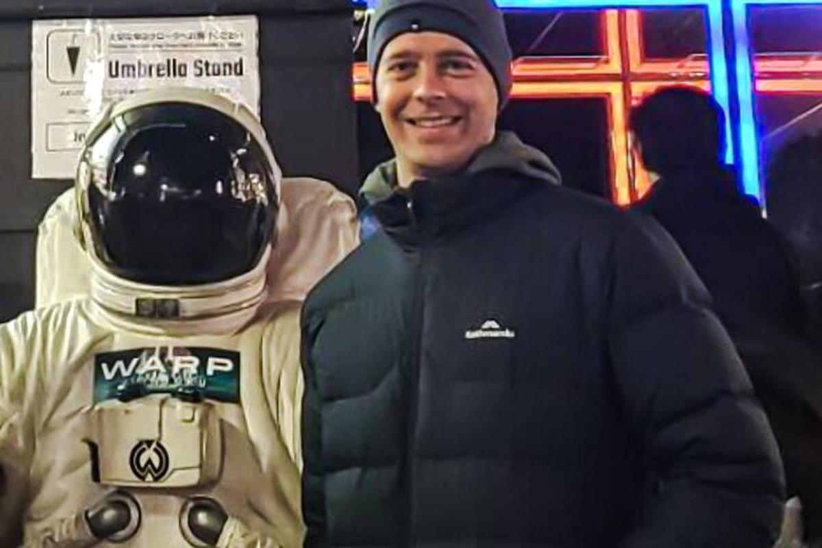 a man standing next to a man wearing a helmet