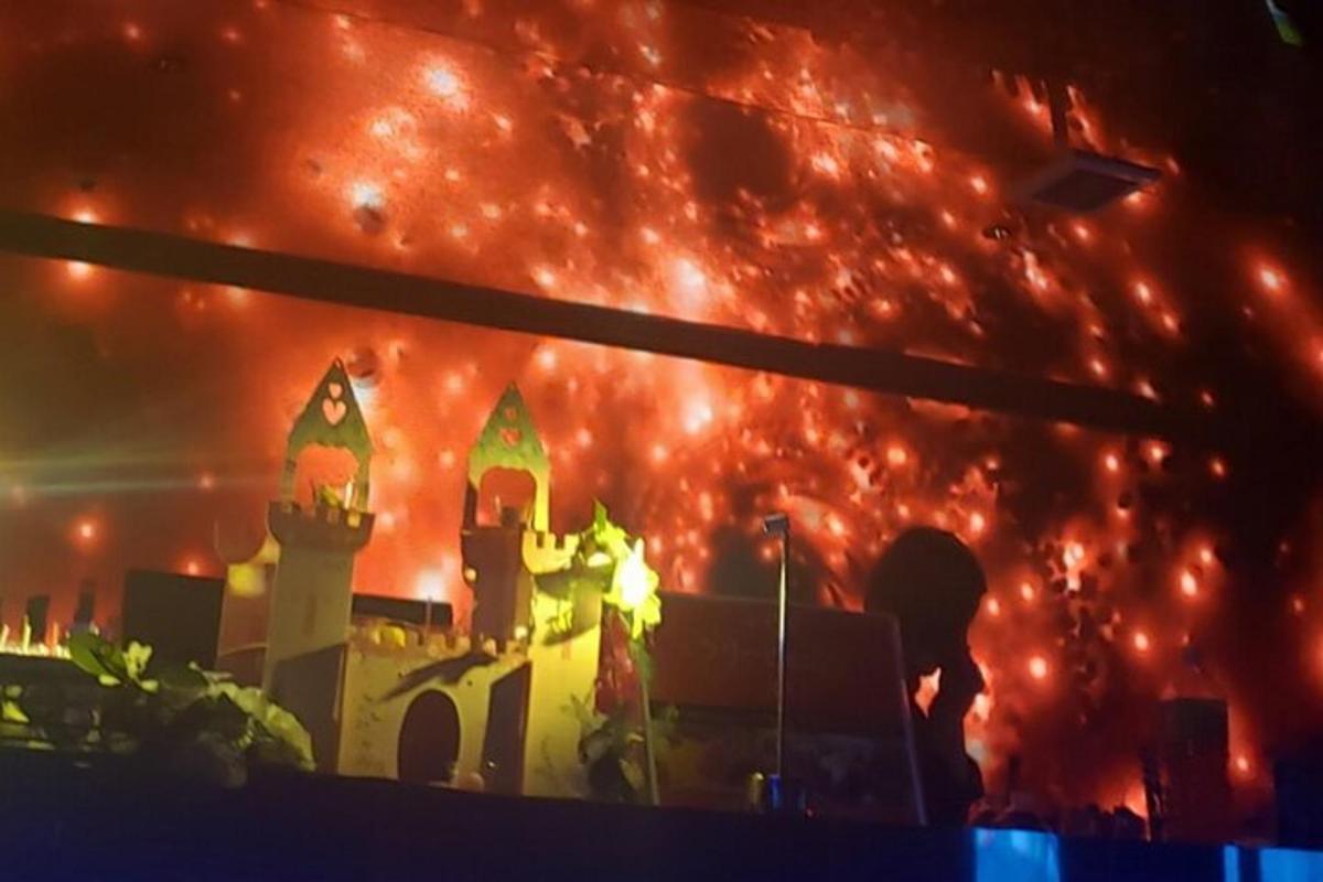 a fire burns behind a castle in front