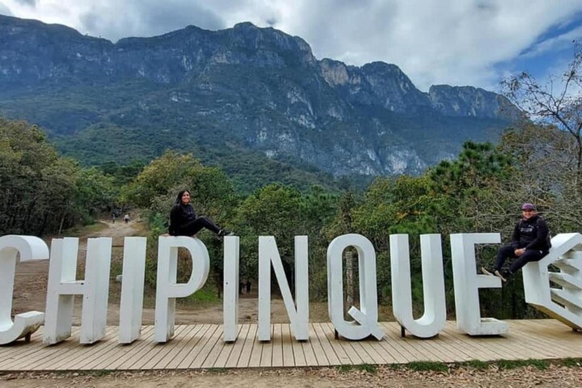 two people sitting on a large sign with mountains in the background