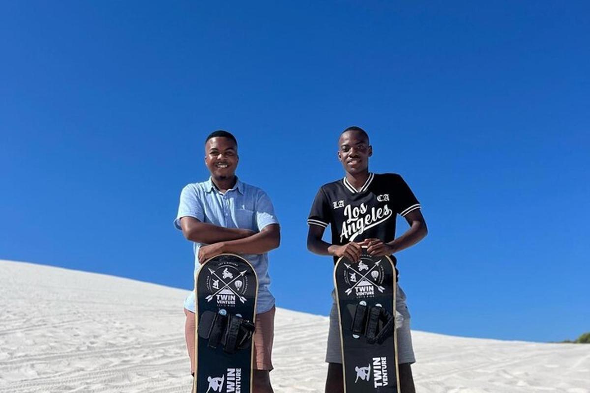 dos homes drets a la sorra sostenint les seves taules de snowboard
