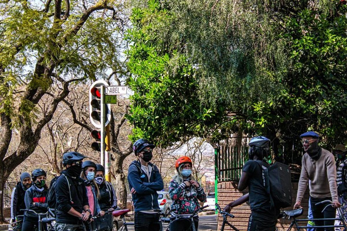 a group of people wearing masks standing next to a traffic light