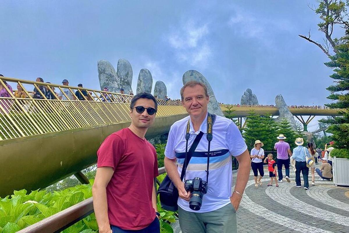 two men standing in front of a bridge with a camera