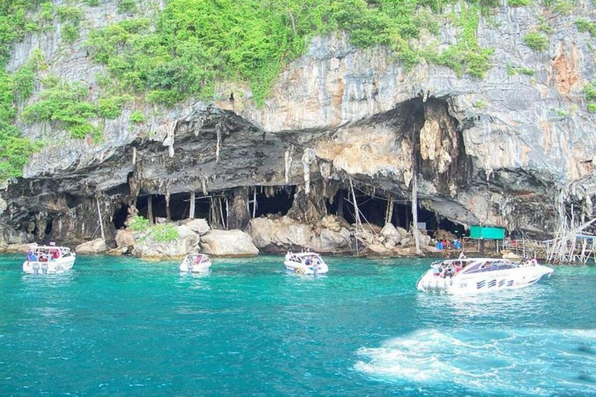 tiga perahu di air di depan sebuah gua