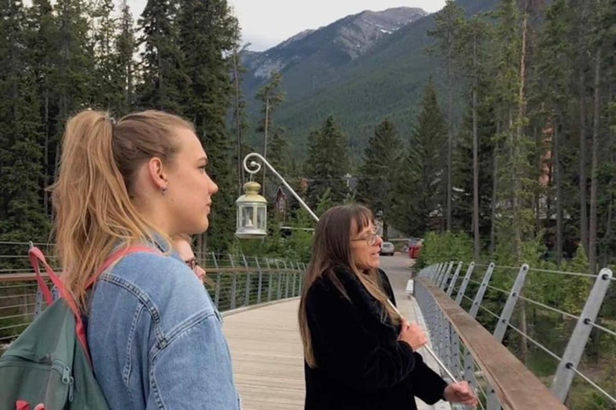 two women standing on a bridge in the mountains
