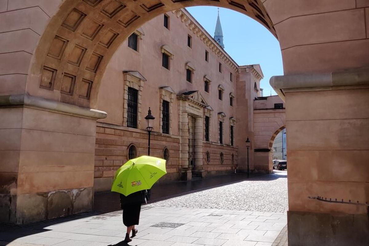 osoba se zeleným deštníkem kráčející po ulici