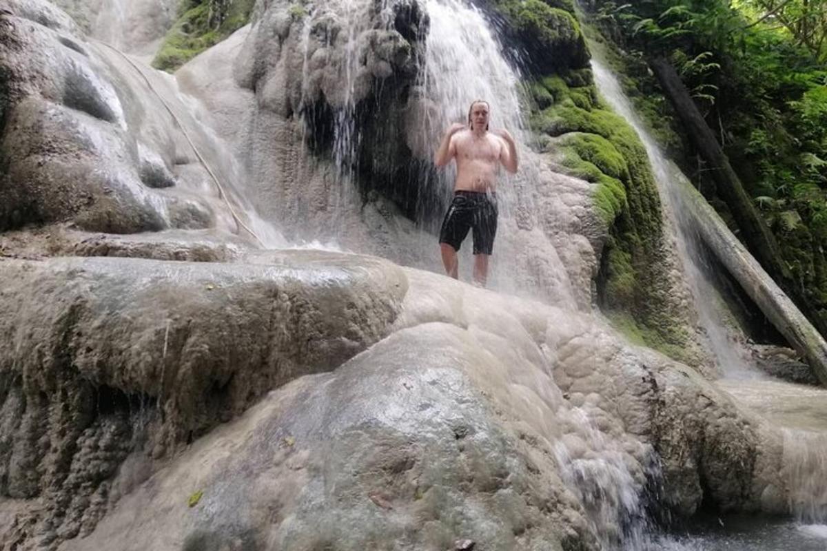 seorang lelaki berdiri di hadapan air terjun