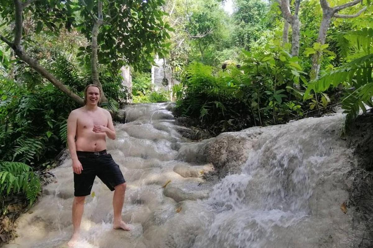 seorang lelaki berdiri di hadapan air terjun