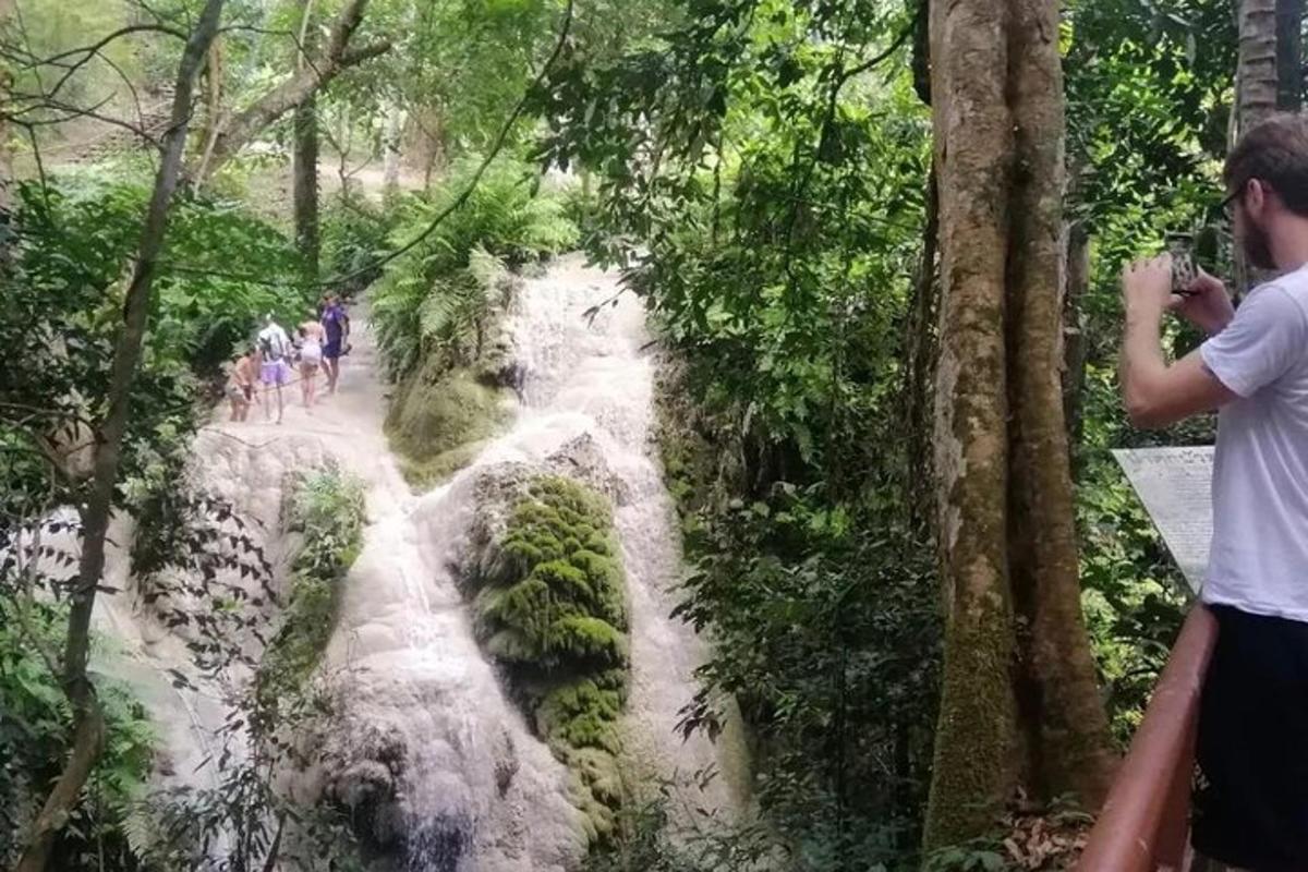 seorang lelaki mengambil gambar air terjun di dalam hutan