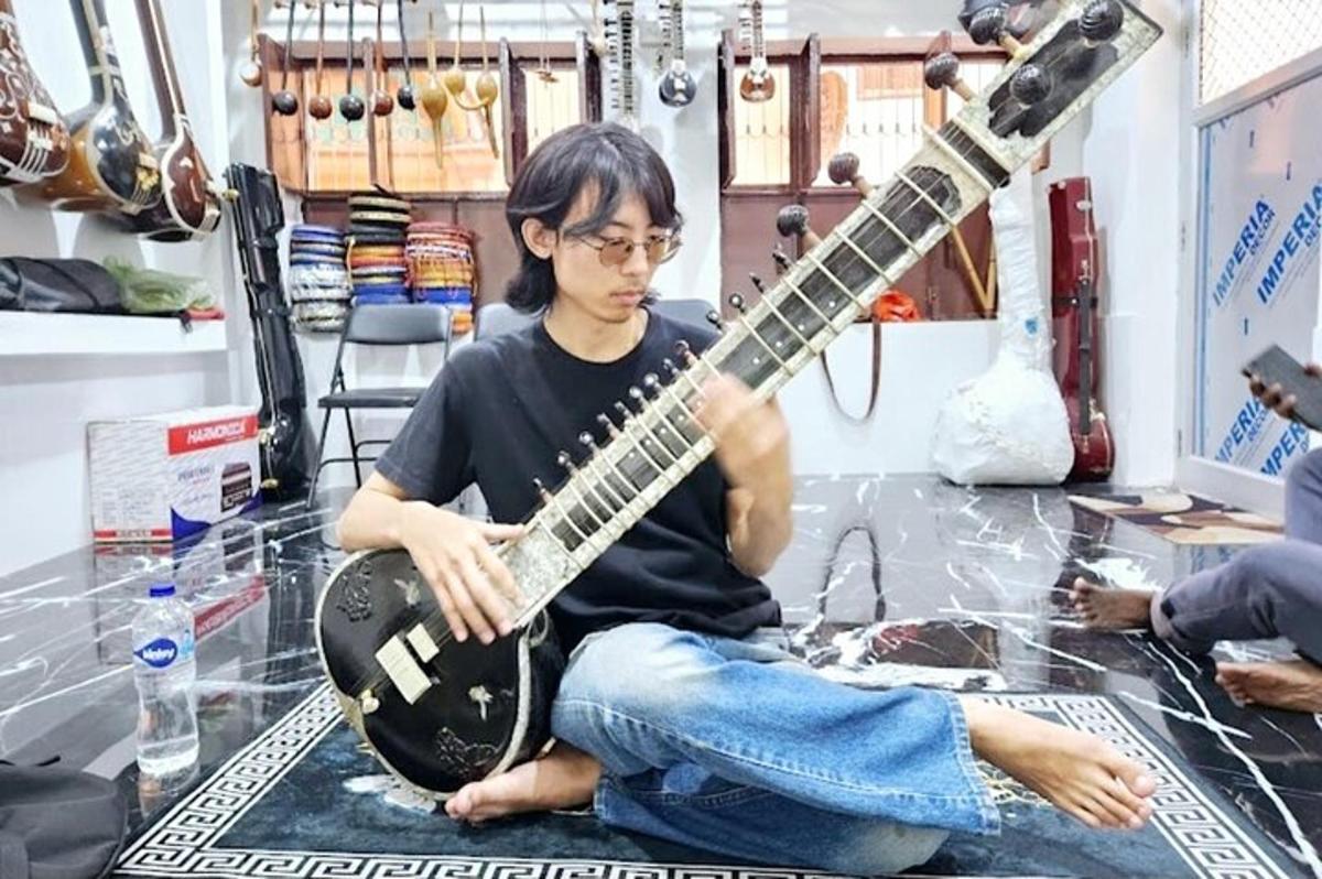 床に座ってギターを弾いている男性