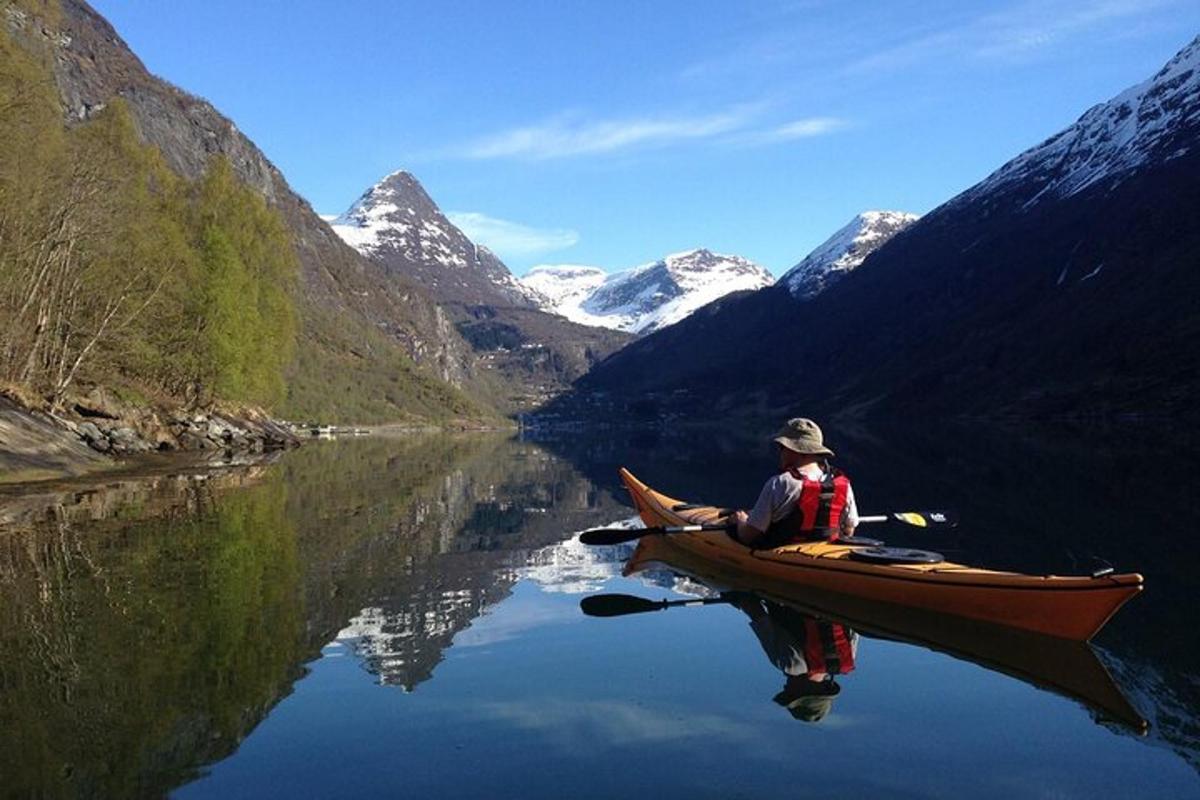 a man in a canoe on a lake with mountains